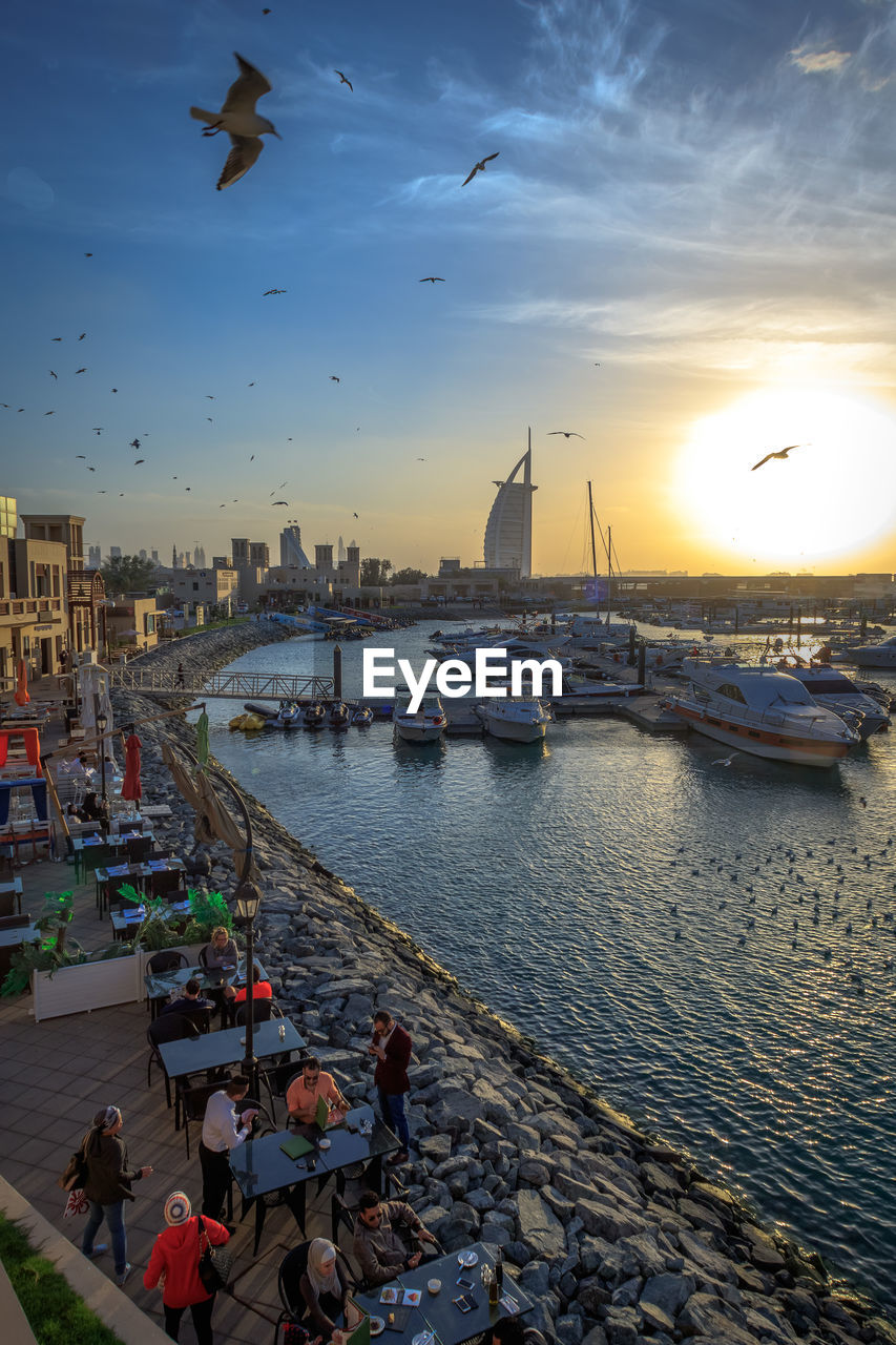 High angle view of yachts moored on river in city at sunset