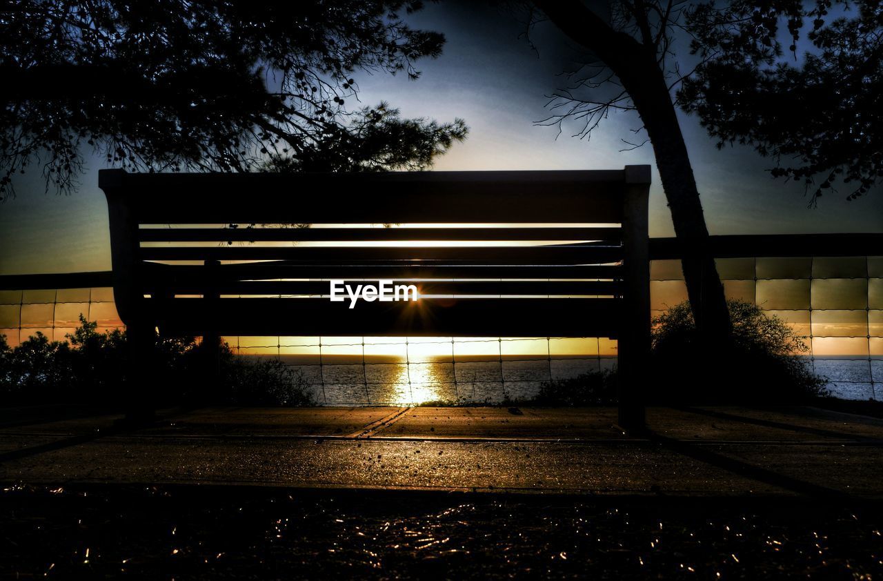 Silhouette bench on footpath during sunset