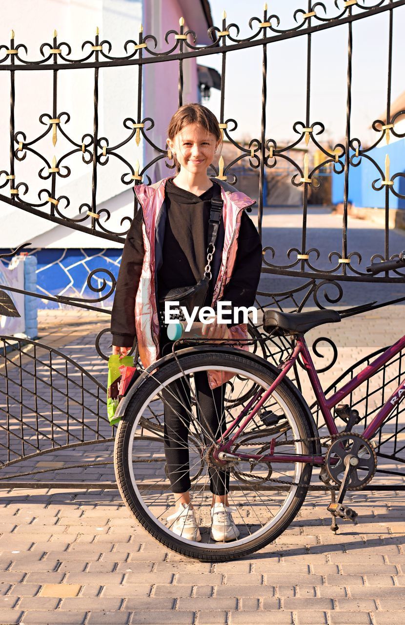 Full length portrait of teenage girl standing on railing