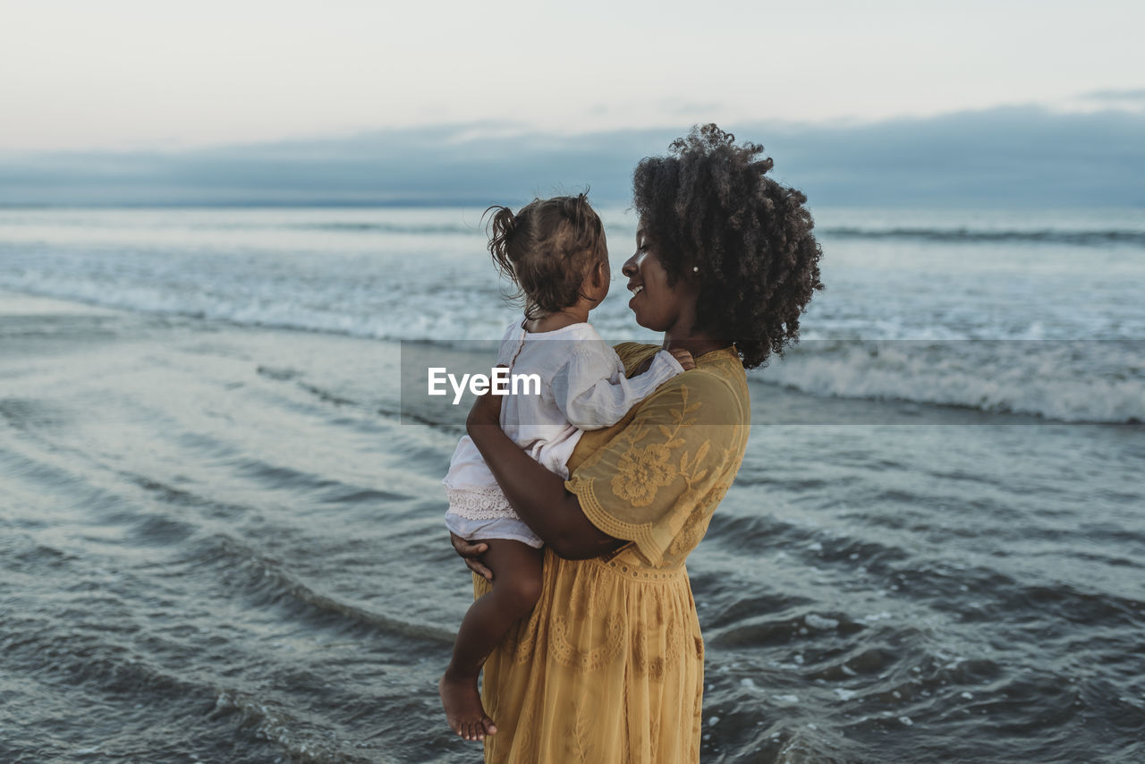 Side view of mother and daughter embracing in the ocean