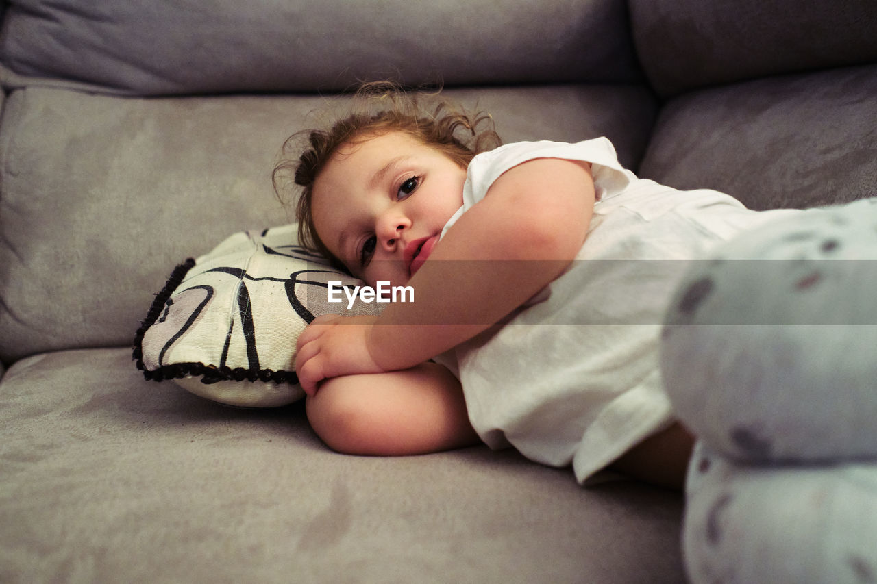 Little girl watches tv resting on the couch