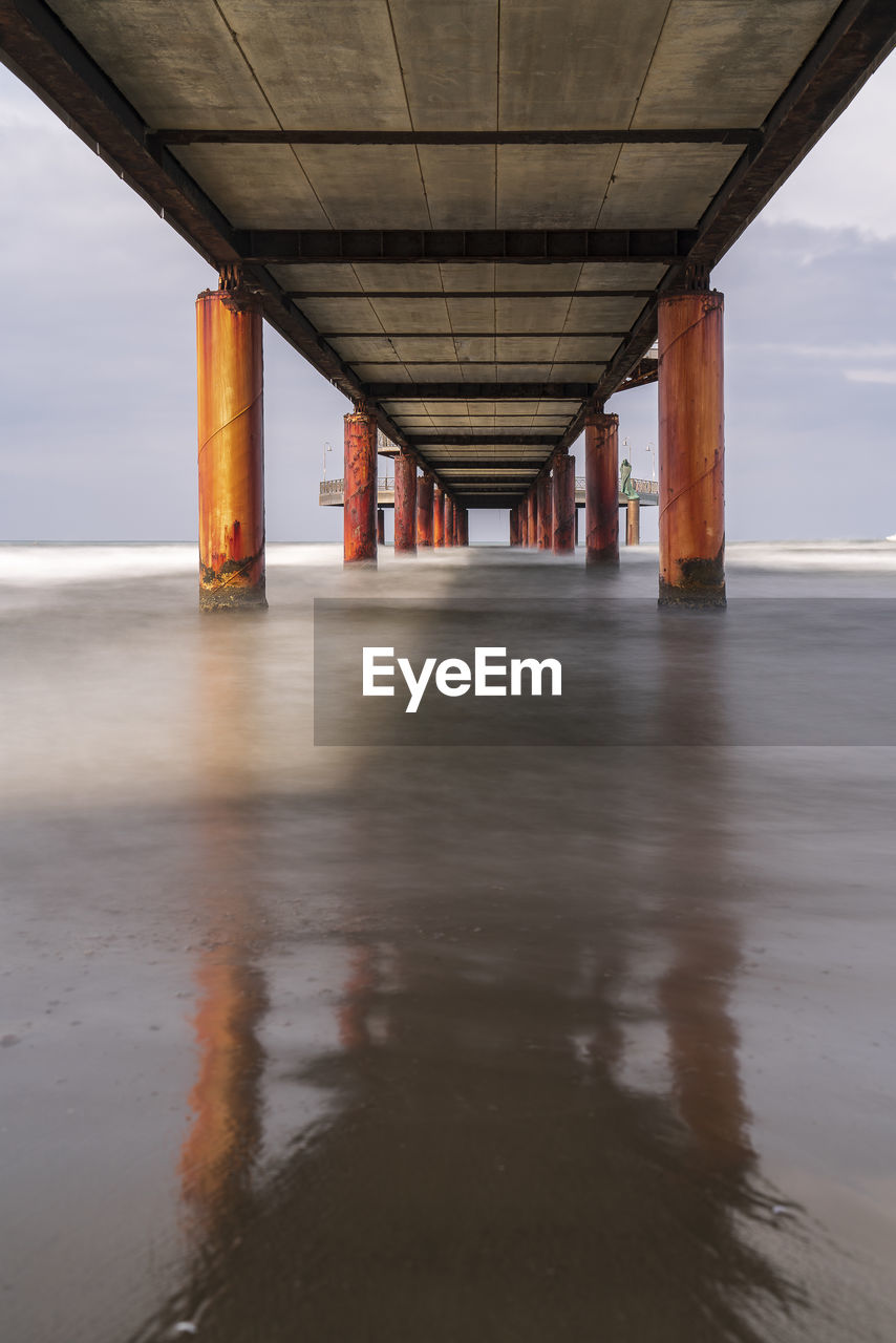 water, architecture, reflection, built structure, bridge, architectural column, sea, transportation, wood, nature, sky, no people, beach, land, day, outdoors, cloud, beam bridge, pier, environment, coast, tranquility, horizon over water, horizon, below