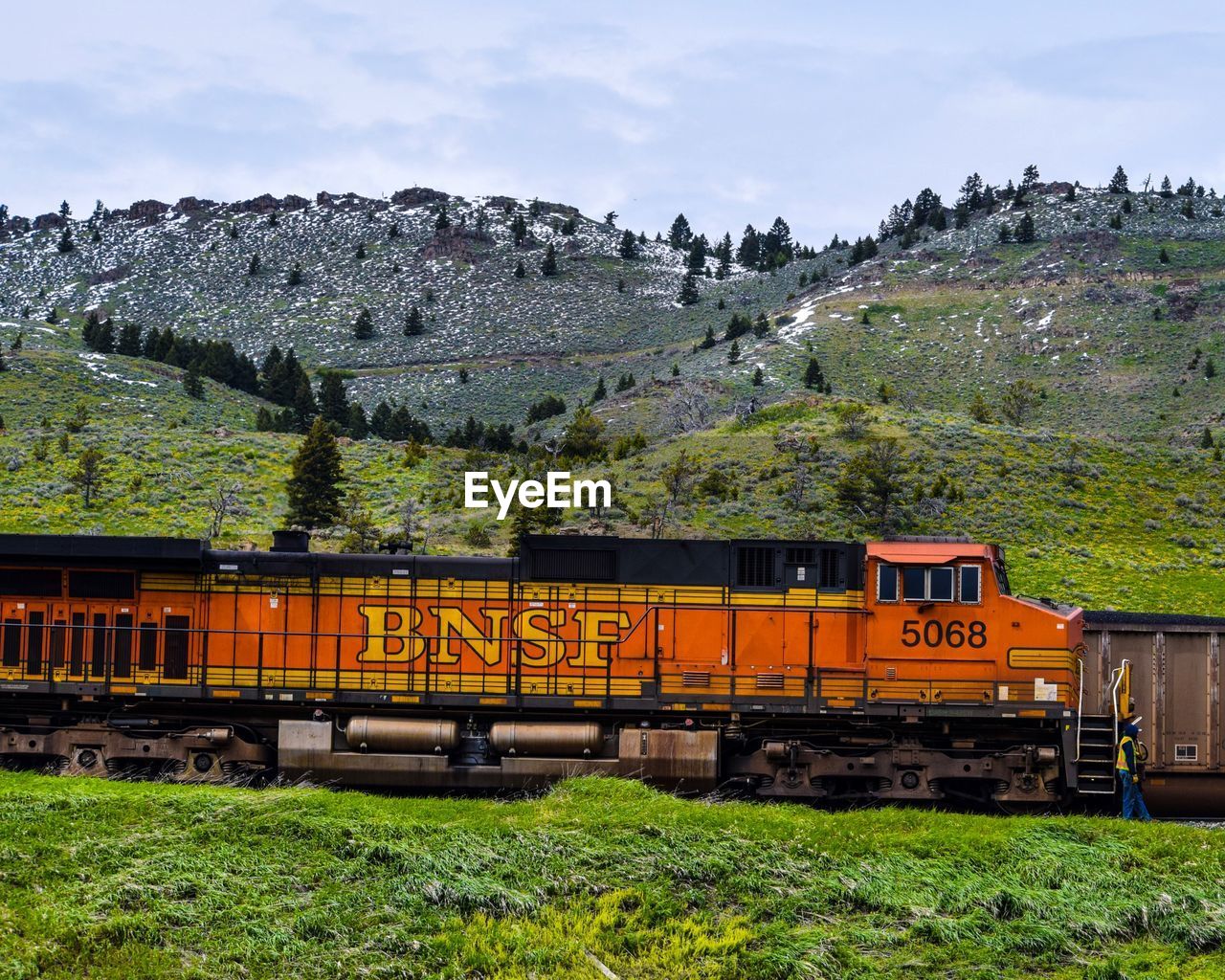 TRAIN ON RAILROAD TRACK BY MOUNTAIN