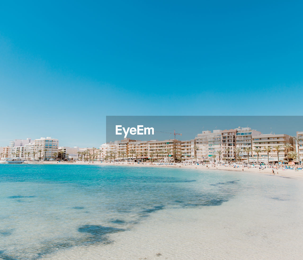 Sea and buildings against clear blue sky