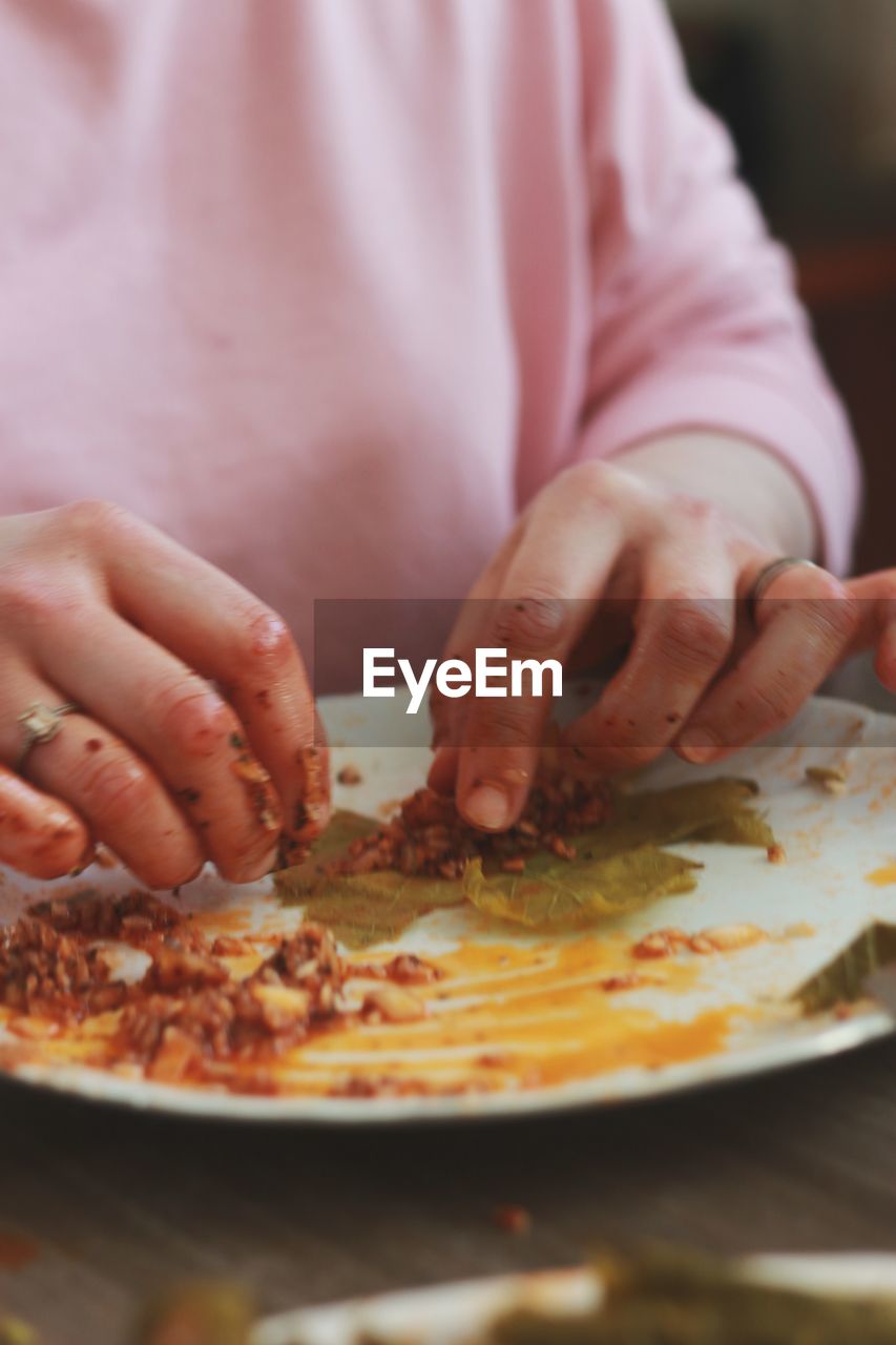 CLOSE-UP OF HAND HOLDING PIZZA IN PLATE