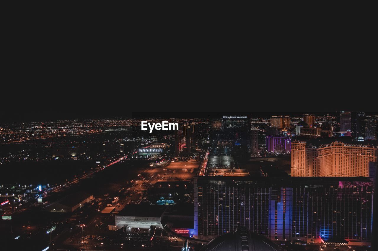 HIGH ANGLE VIEW OF ILLUMINATED MODERN BUILDINGS IN CITY AT NIGHT