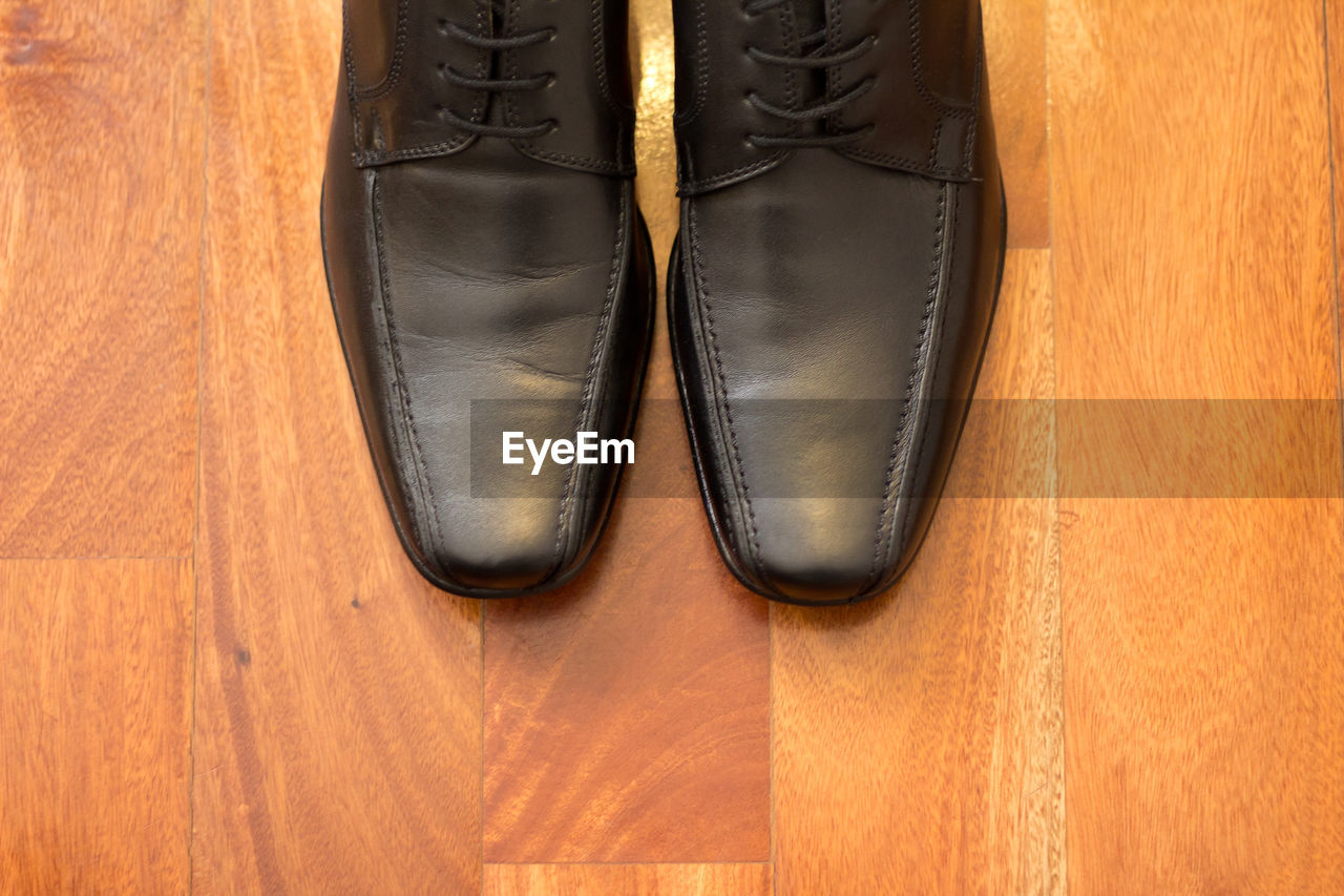High angle view of black leather shoes on hardwood floor