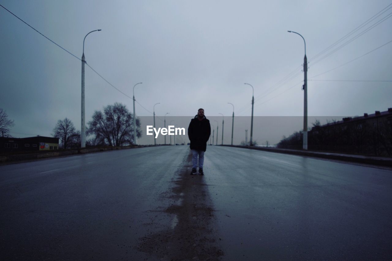 REAR VIEW OF MAN STANDING ON STREET