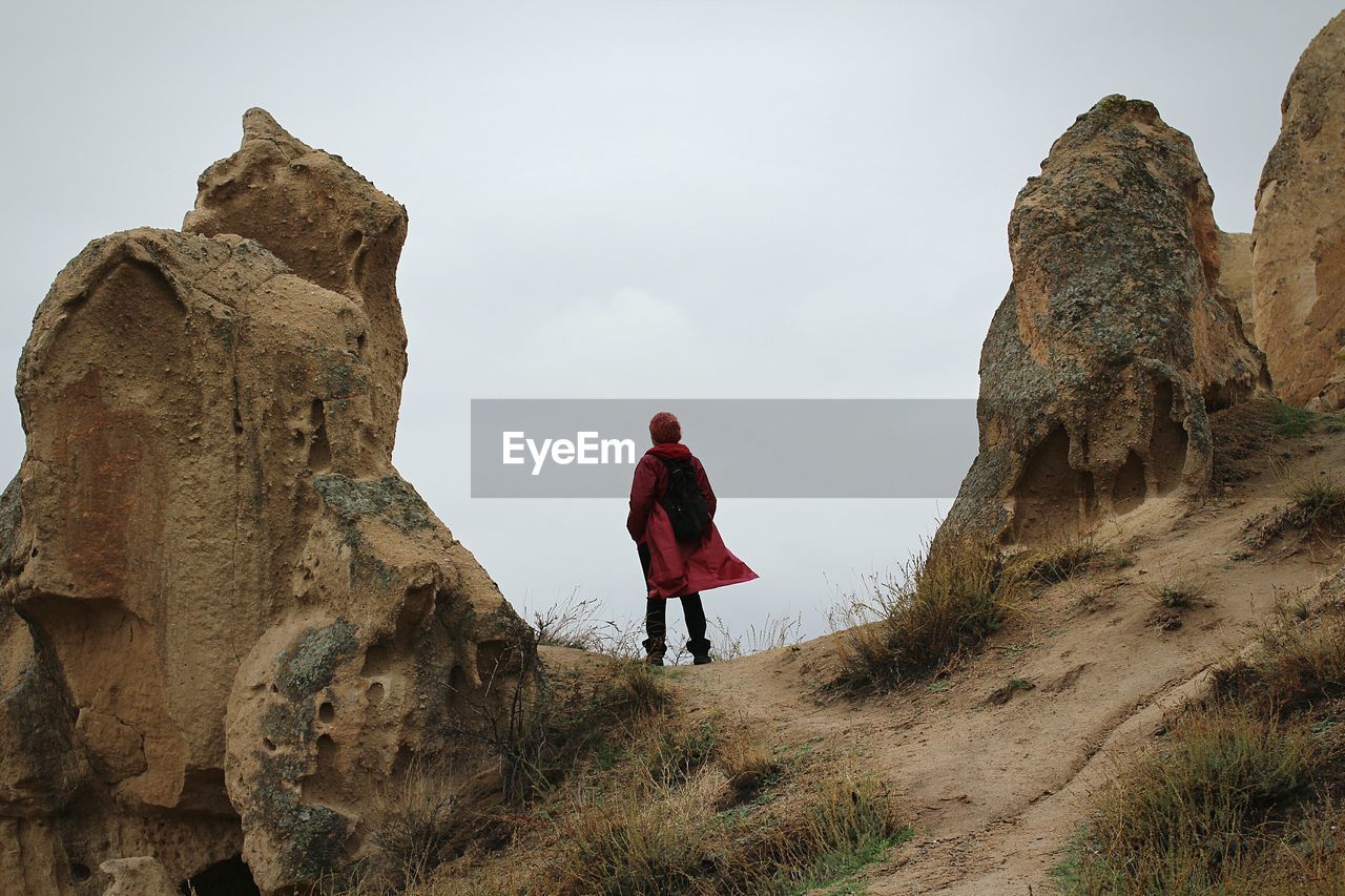 Rear view of hiker amidst rock formation against sky at cappadocia