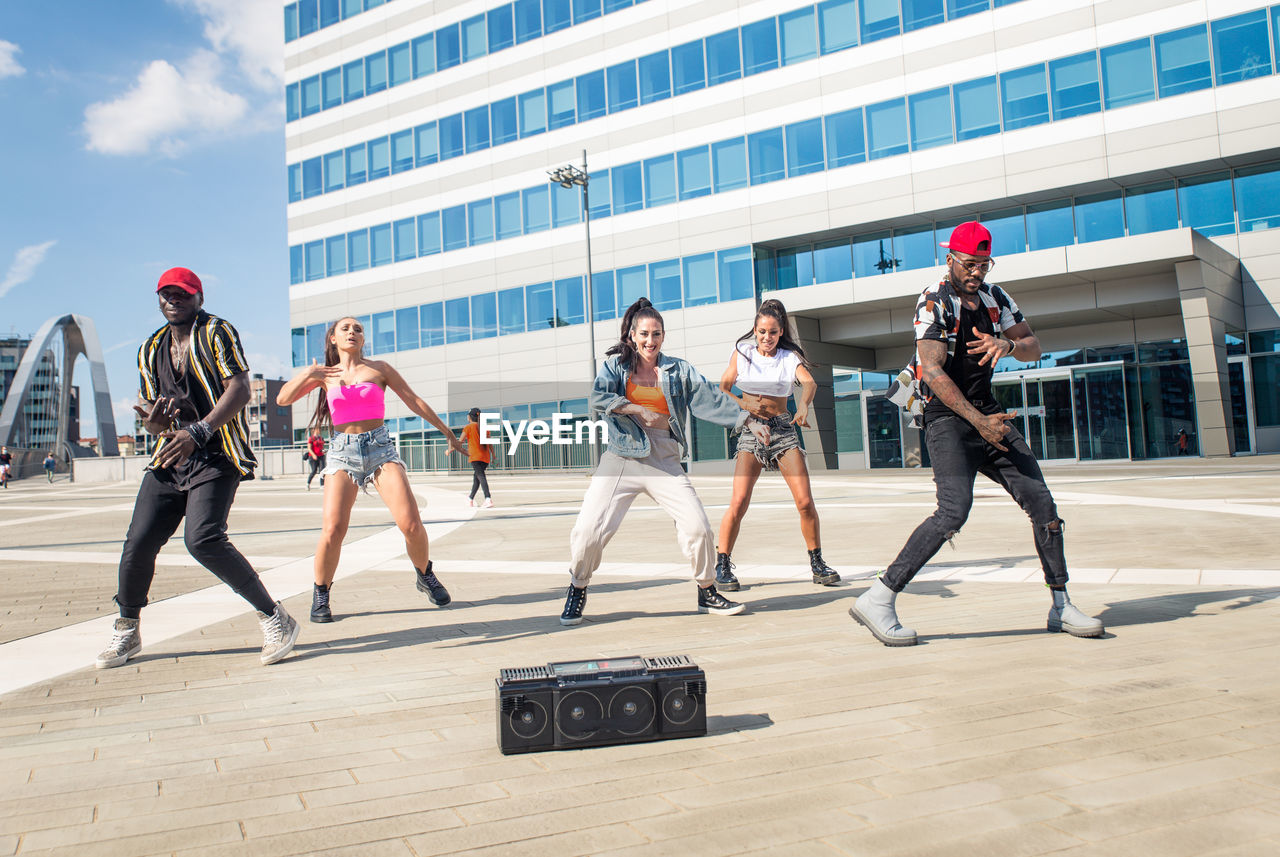 Friends dancing against building in city