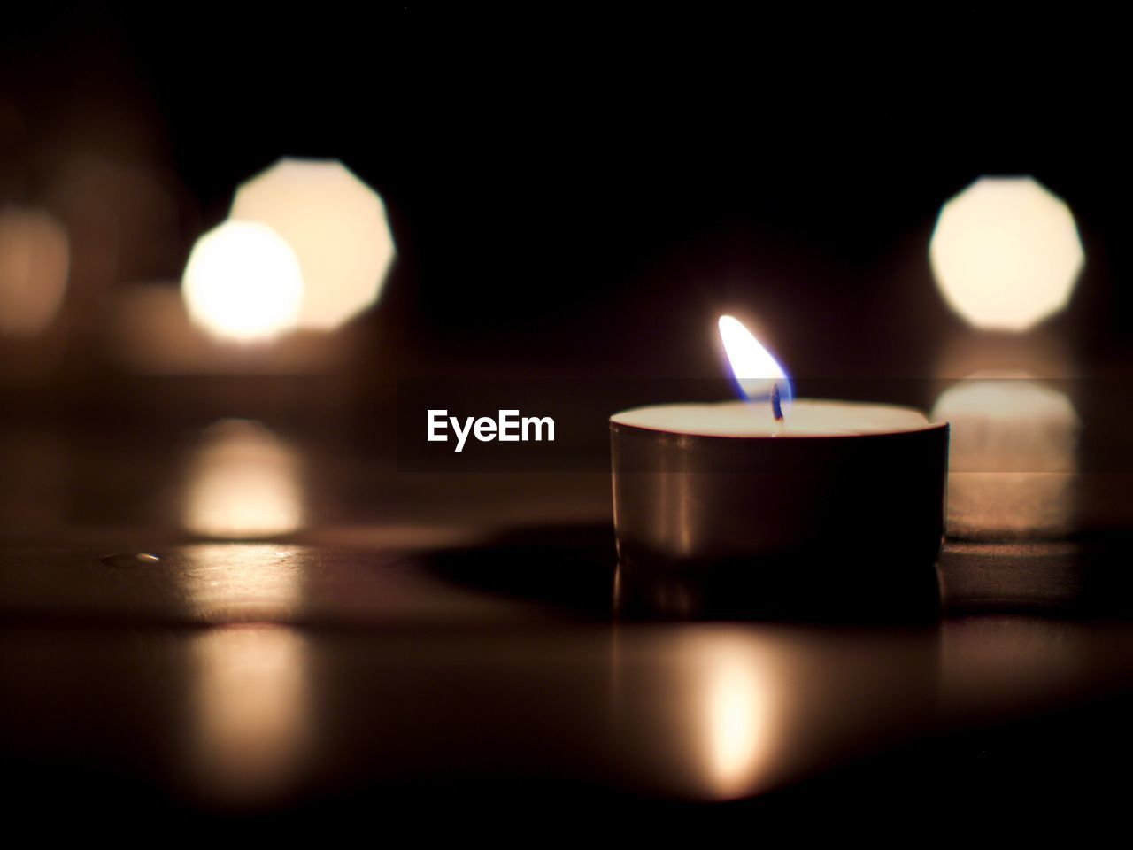 CLOSE-UP OF LIT CANDLE IN DARKROOM