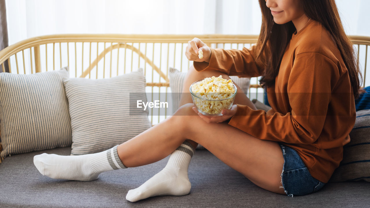 Midsection of woman sitting on sofa at home