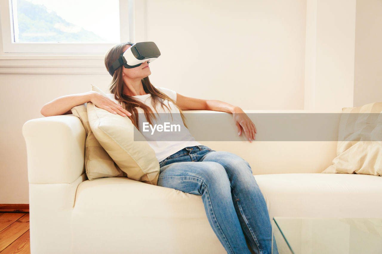 Mid adult woman using virtual reality stimulator at home