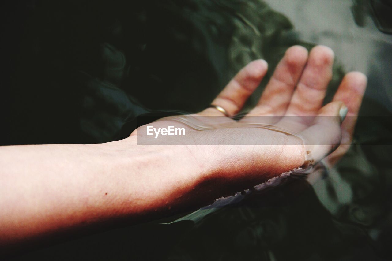Cropped image of woman hand floating on lake