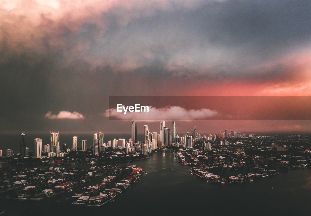 Buildings and sea in city against sky during sunset