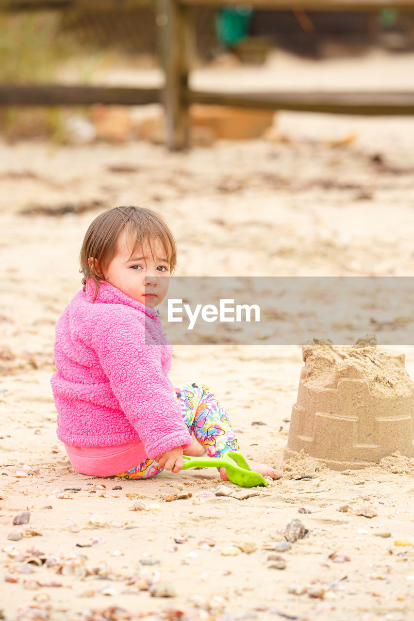 Young child building sand castle, cool day at beach