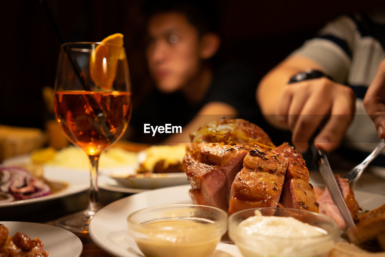 Midsection of man cutting meat on table at home