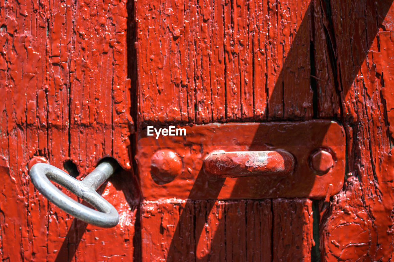 Antique iron key from the gate in the old red wooden gate.