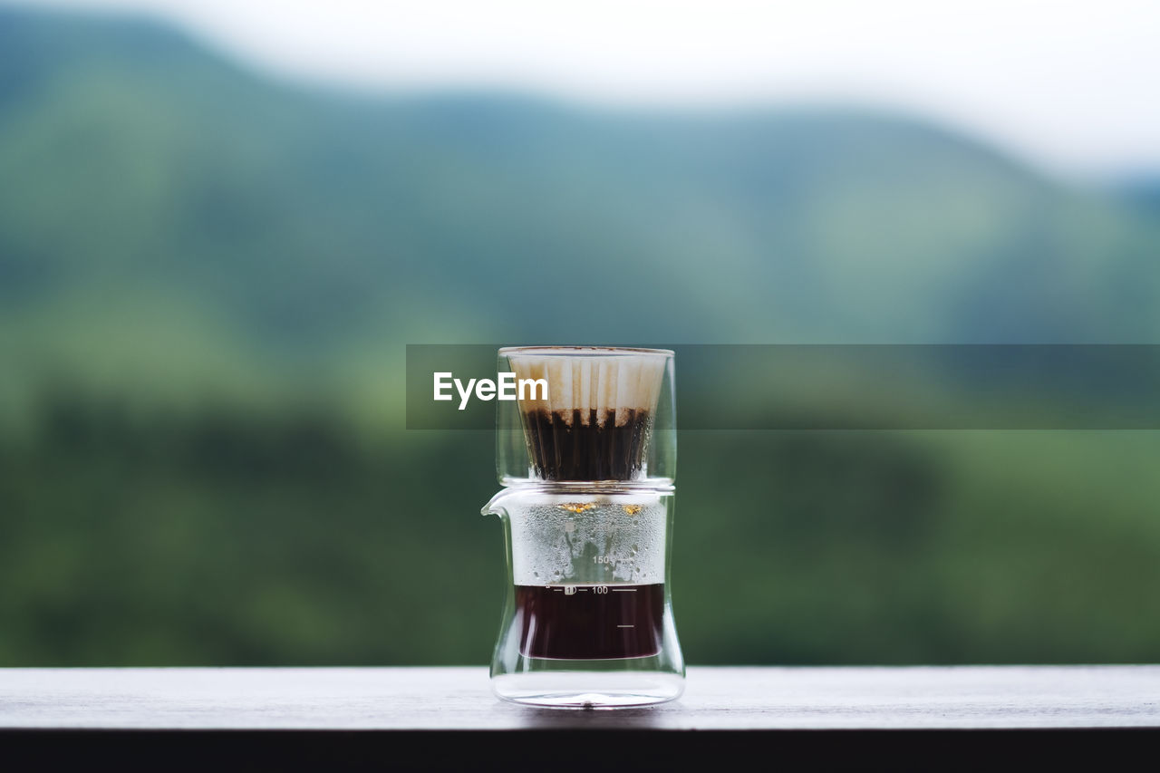 Drip or brewed coffee on wooden table with blurred nature background