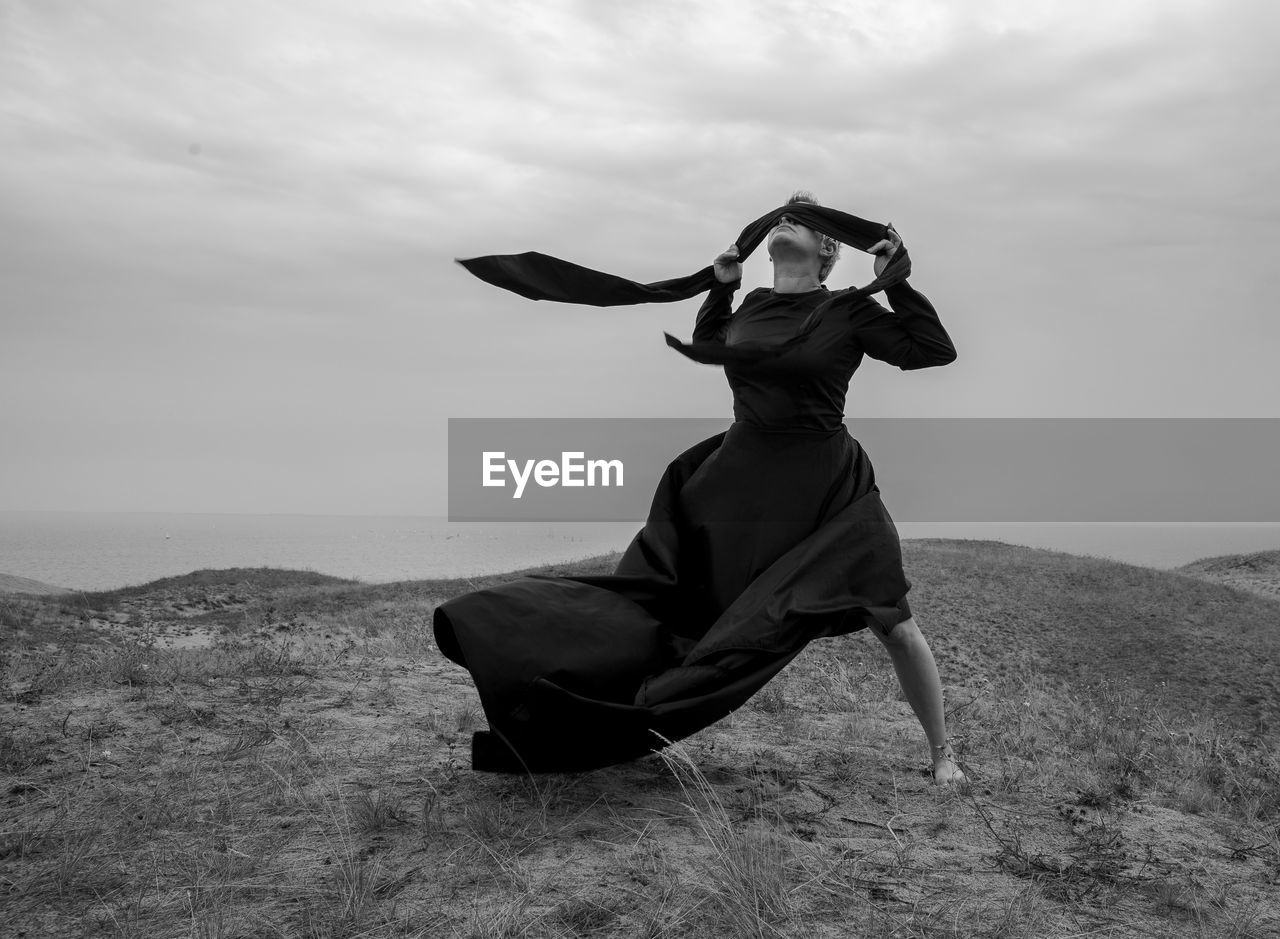 Full length of woman standing on field against sky