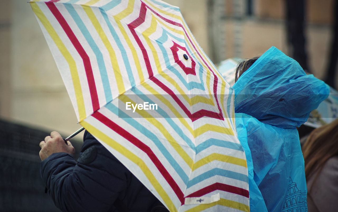 LOW SECTION OF PEOPLE HOLDING MULTI COLORED UMBRELLA