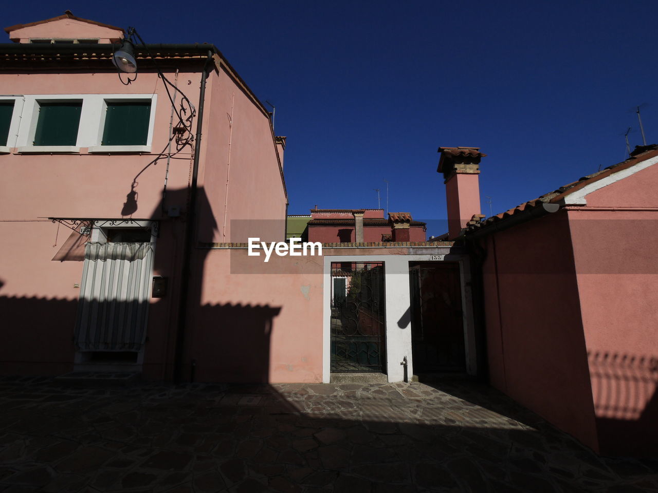 Low angle view of buildings against clear blue sky of burano close  venice, italy.