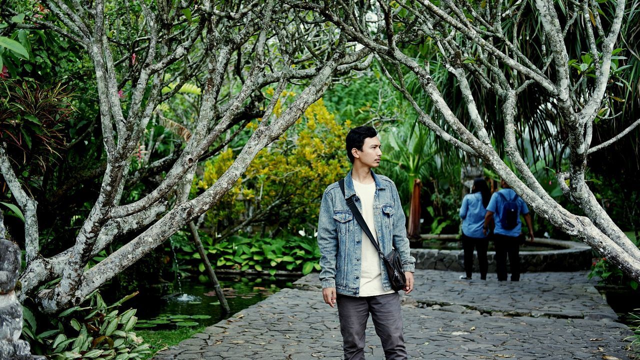 Thoughtful young man standing amidst bare branches