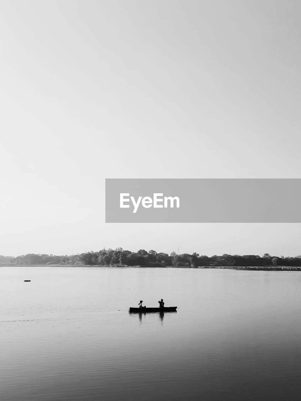 water, lake, sky, copy space, tranquility, nature, black and white, tranquil scene, scenics - nature, beauty in nature, silhouette, transportation, reflection, monochrome photography, nautical vessel, monochrome, clear sky, day, vehicle, mode of transportation, horizon, men, non-urban scene, morning, outdoors, one person, rowing, distant, idyllic, adult, environment, travel