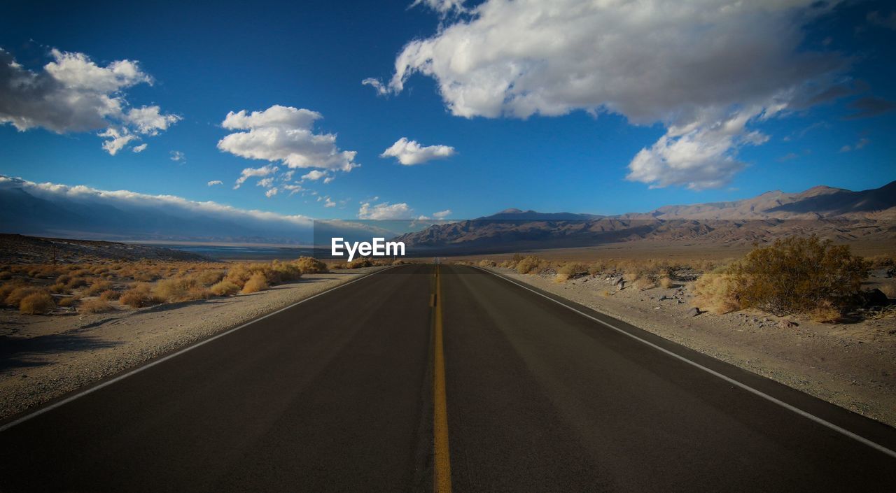 Empty road along landscape against sky