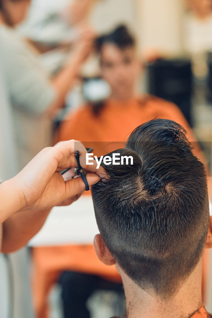 Cropped hands of woman cutting man hair in salon