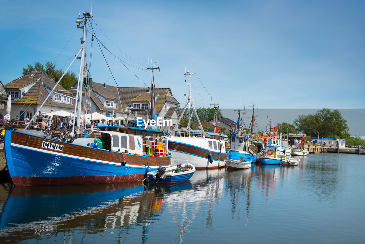 BOATS MOORED IN HARBOR AGAINST SKY