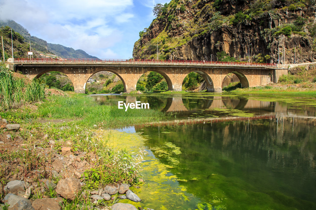 Arch bridge over river against mountains