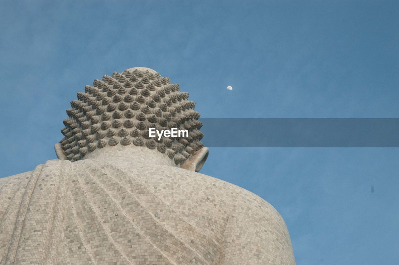 Low angle view of buddha statue against sky at dusk
