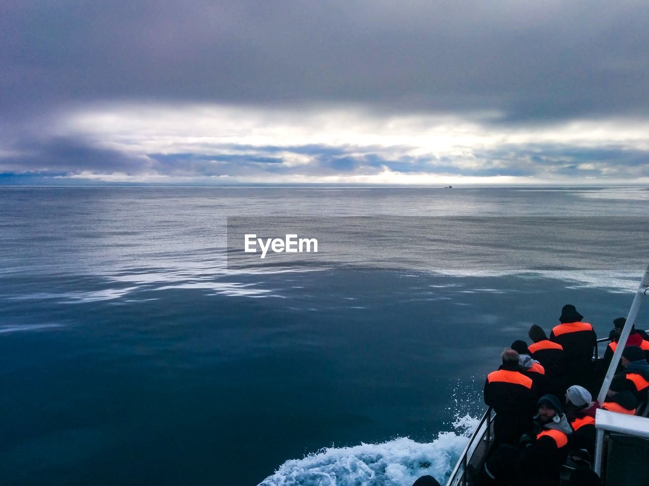 High angle view of people on boat sailing in sea against cloudy sky