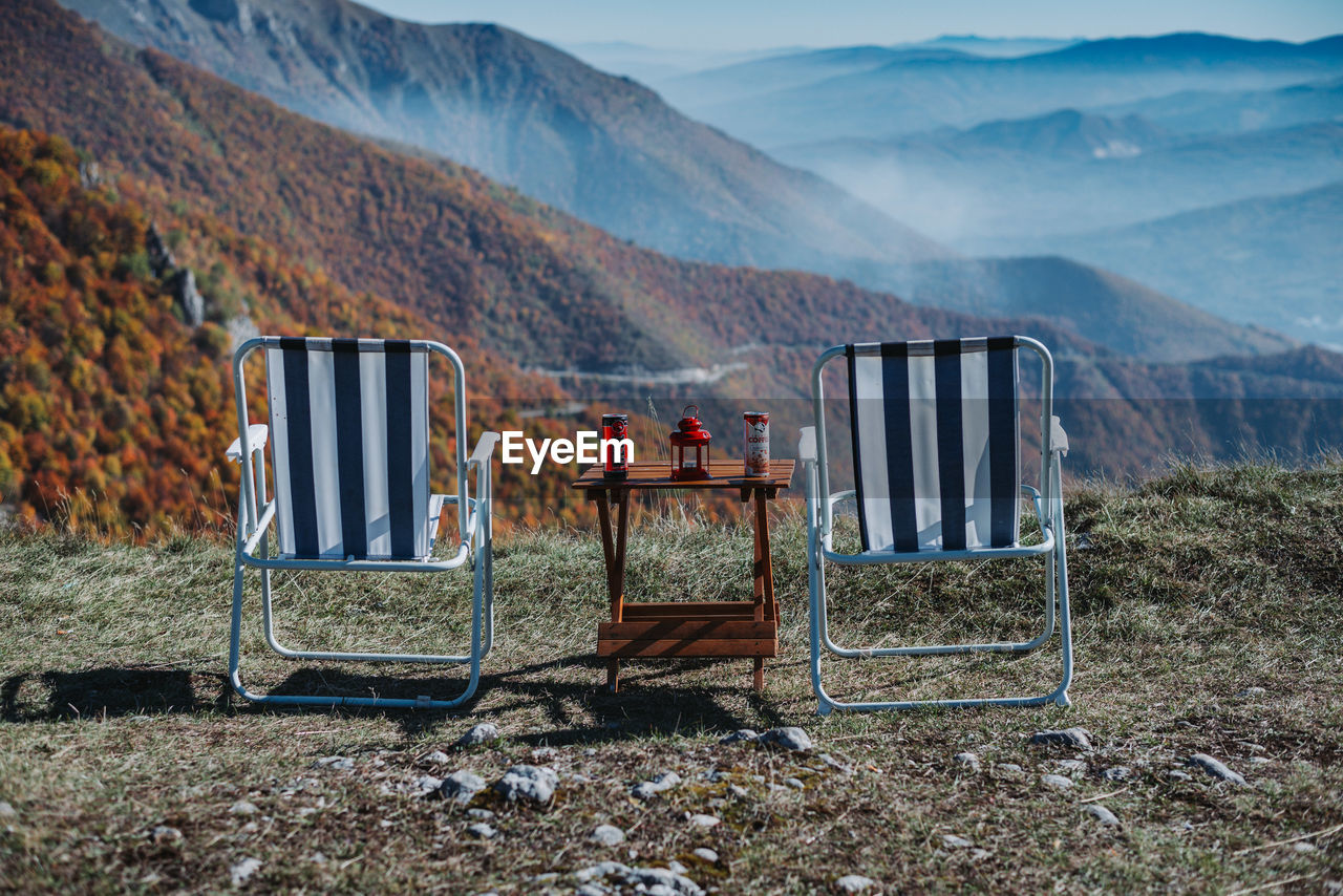 VIEW OF CHAIRS ON FIELD AGAINST MOUNTAINS