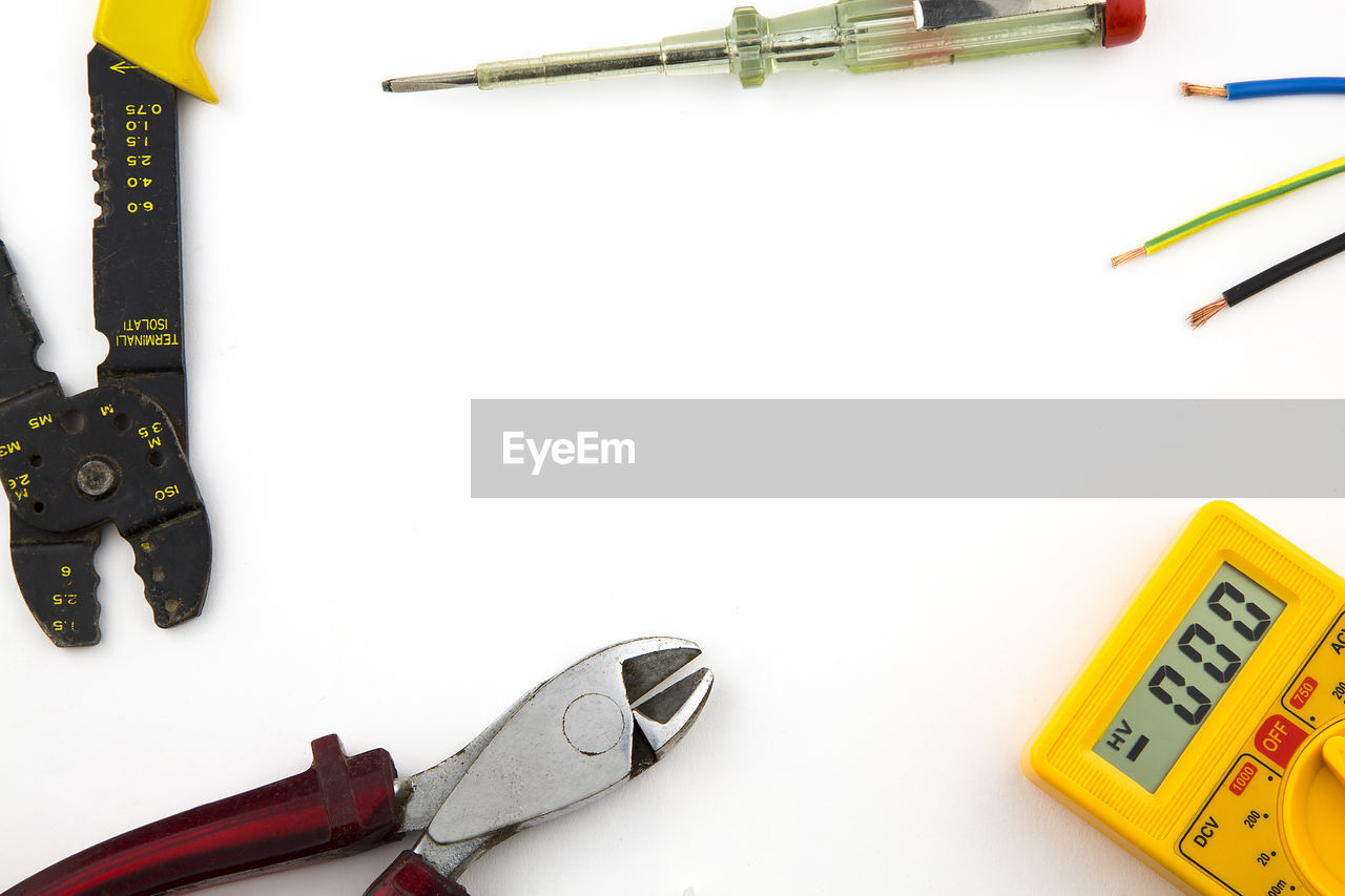 High angle view of multimeter and plier on white table