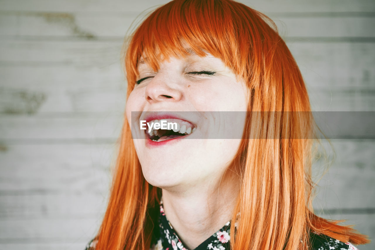 Redhead woman laughing against wall