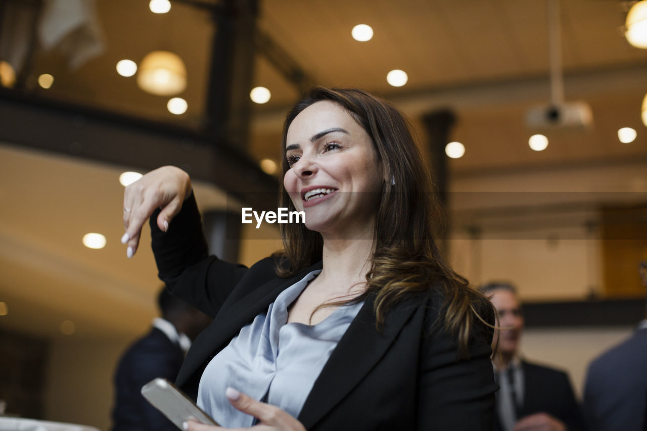 Low angle view of smiling businesswoman gesturing in conference center