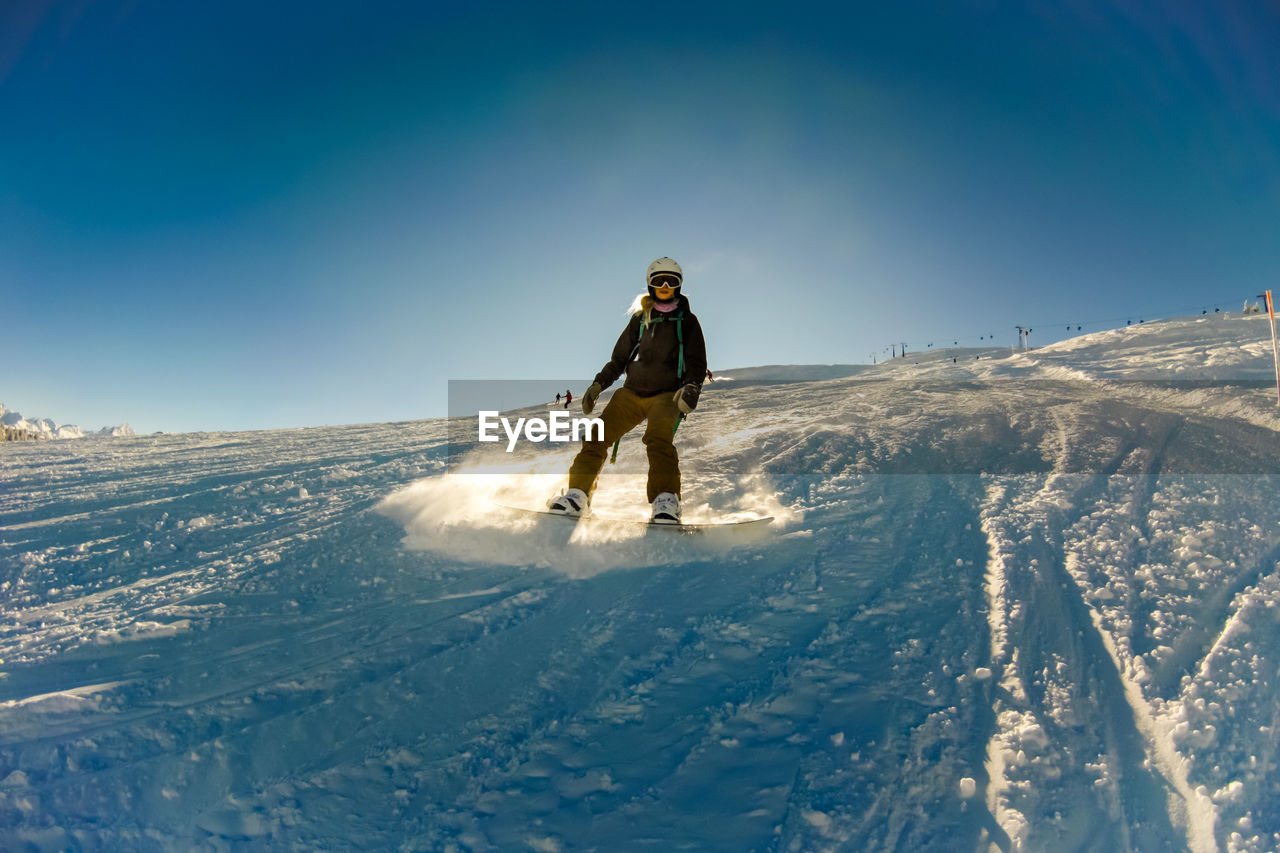 Woman skiing on snow covered mountain against sky