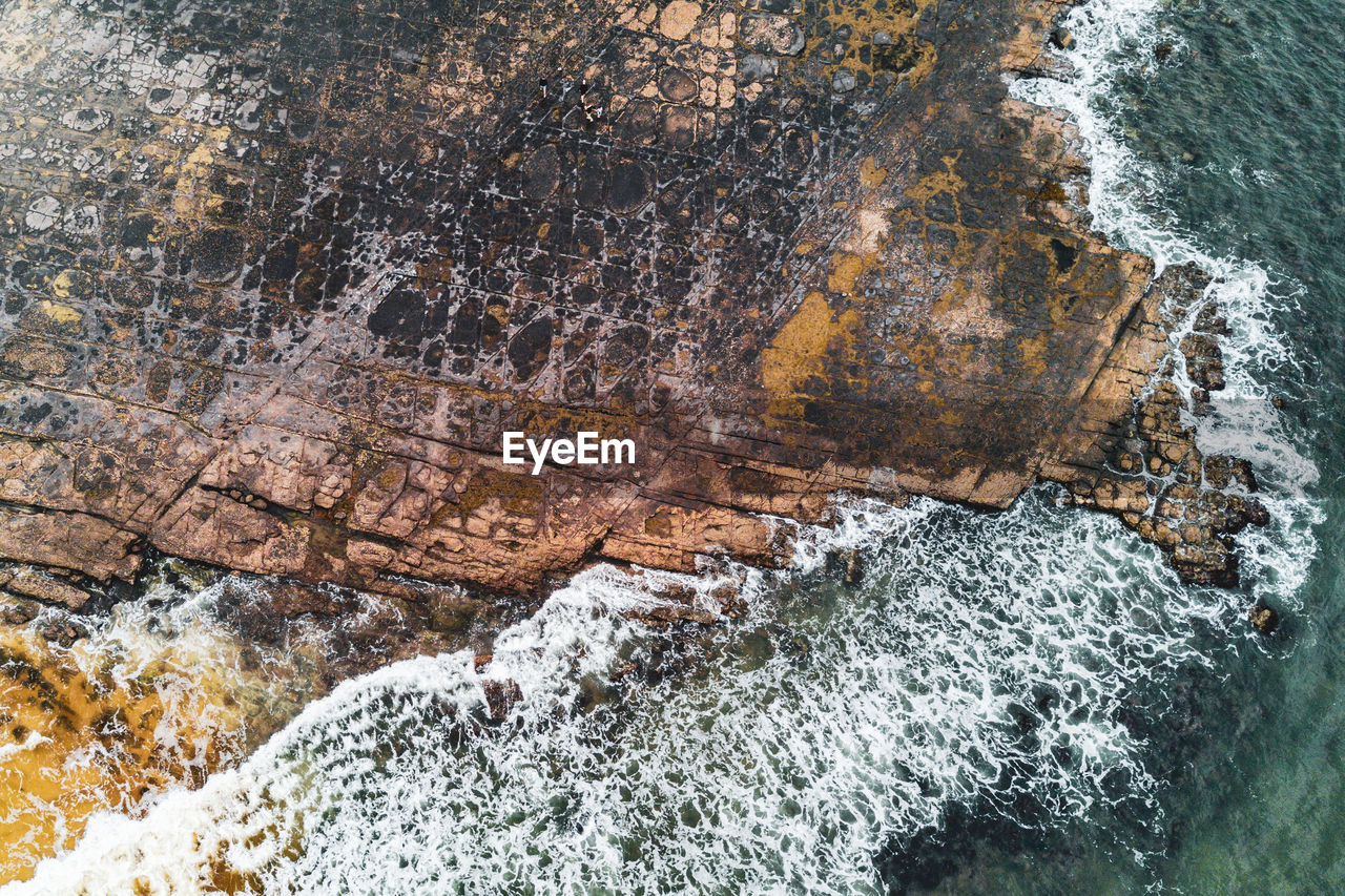 High angle view of waves splashing on rocks