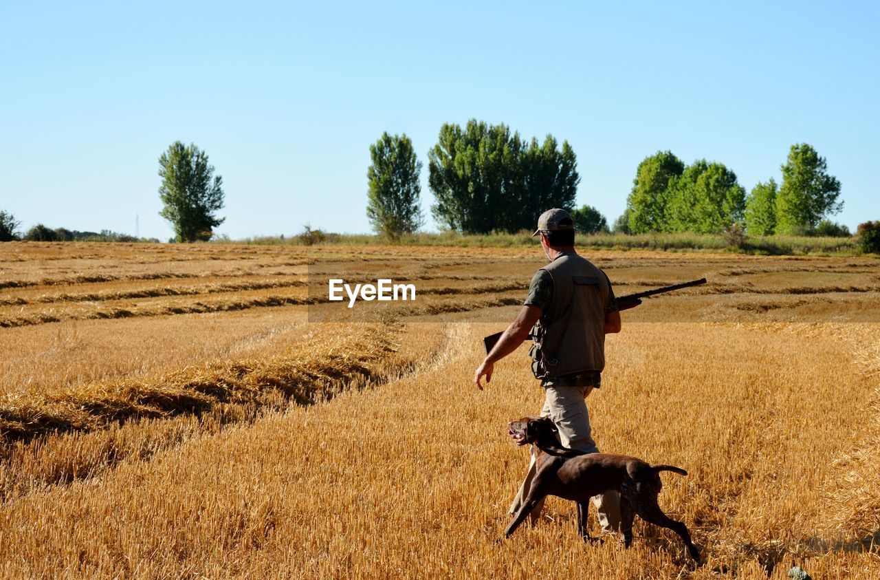 Hunter walking with dog on landscape