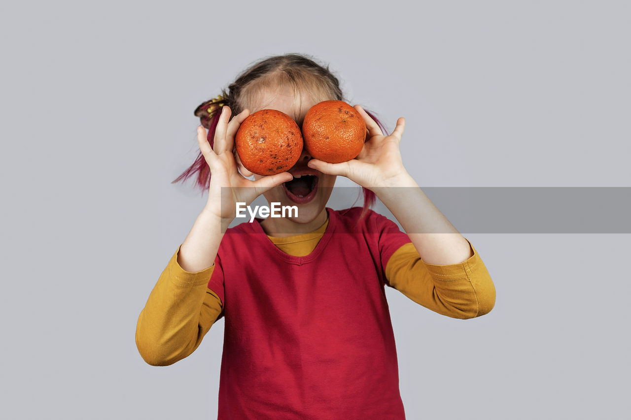 MIDSECTION OF GIRL HOLDING ICE CREAM AGAINST WHITE BACKGROUND