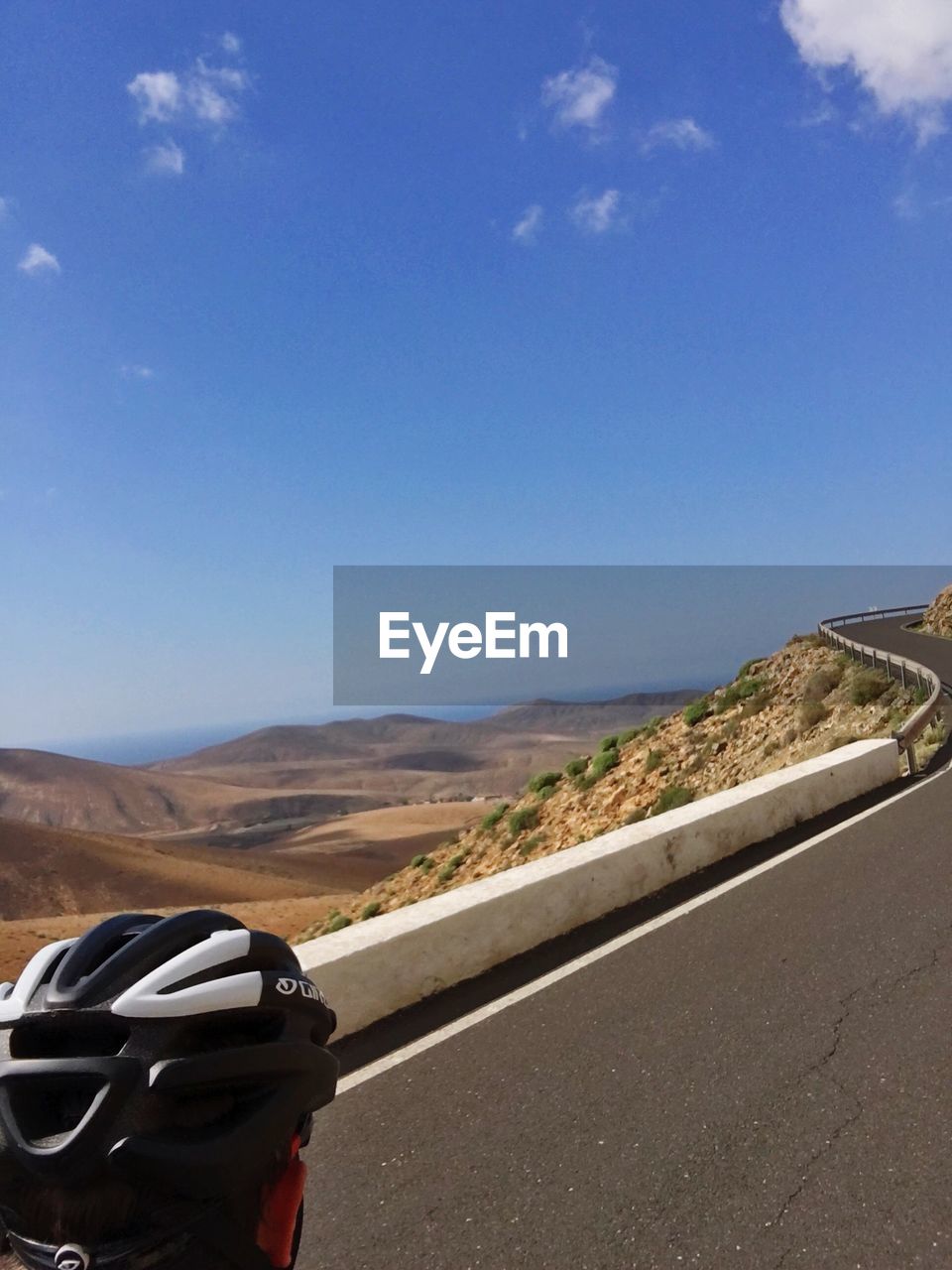 Cropped image of person wearing helmet while riding bicycle on mountain road