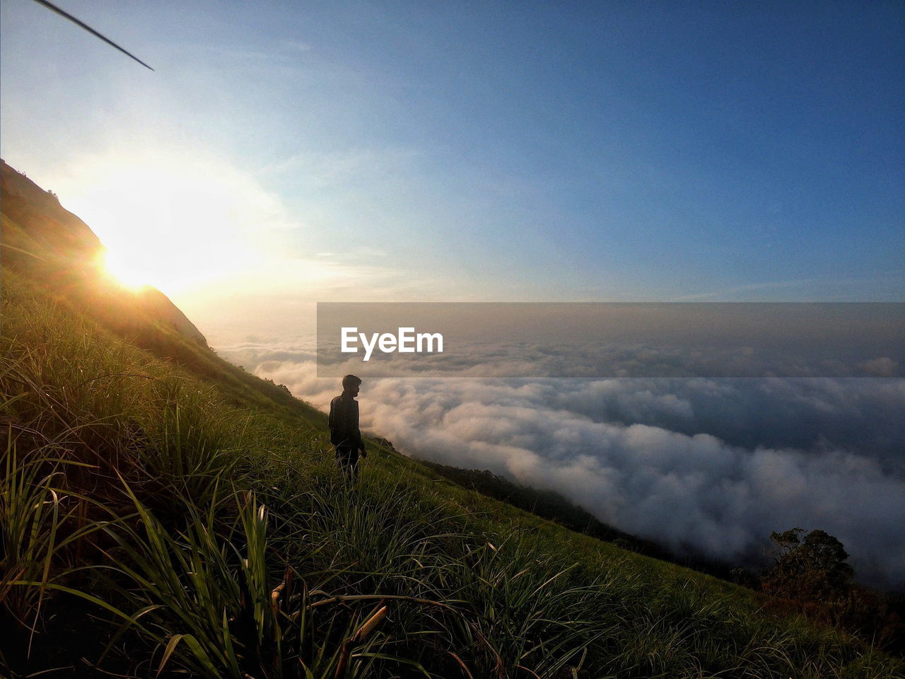 Man standing on field against cloudscape during sunset