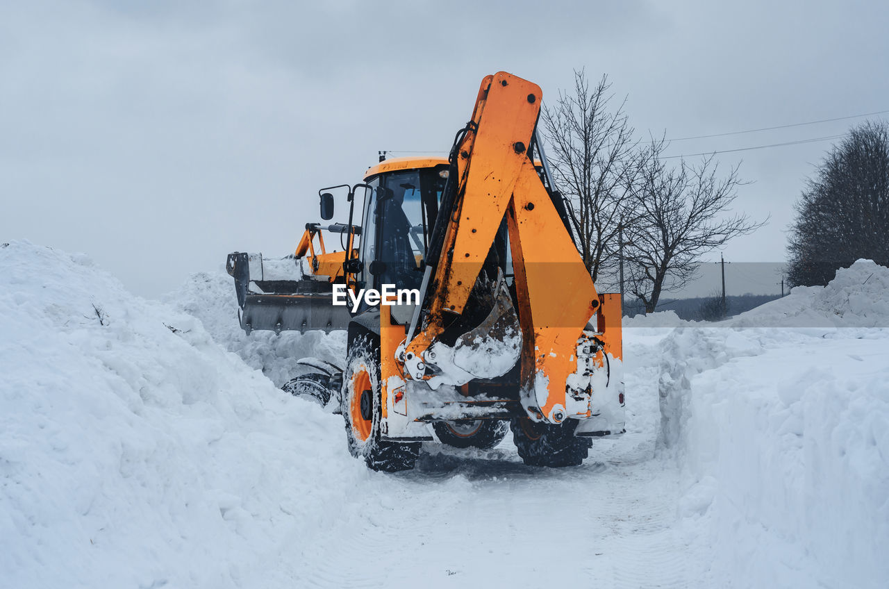 Yellow tractor cleans up snow from road. cleaning and cleaning of roads in city from snow in winter