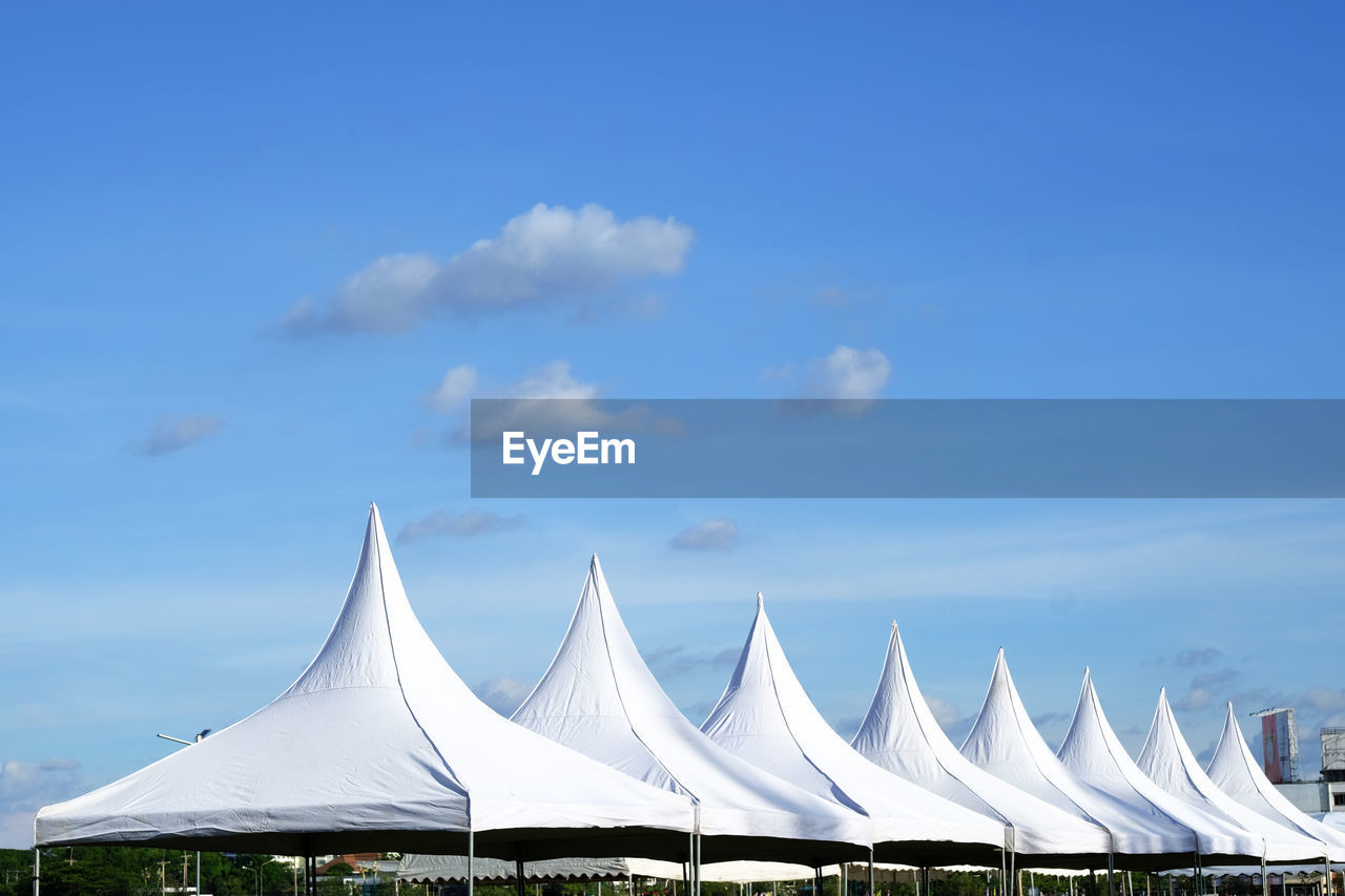 TENT IN ROW AGAINST BLUE SKY