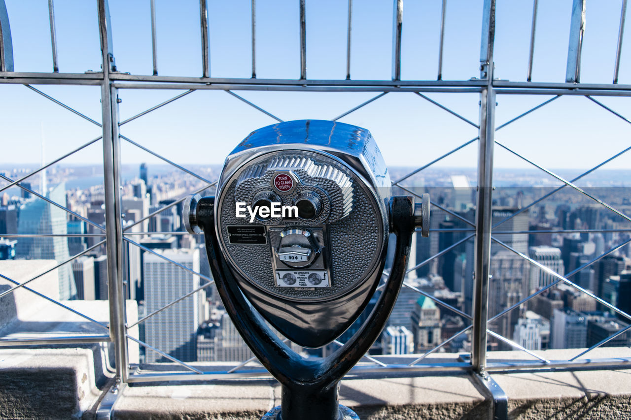 Coin-operated binoculars with cityscape in background