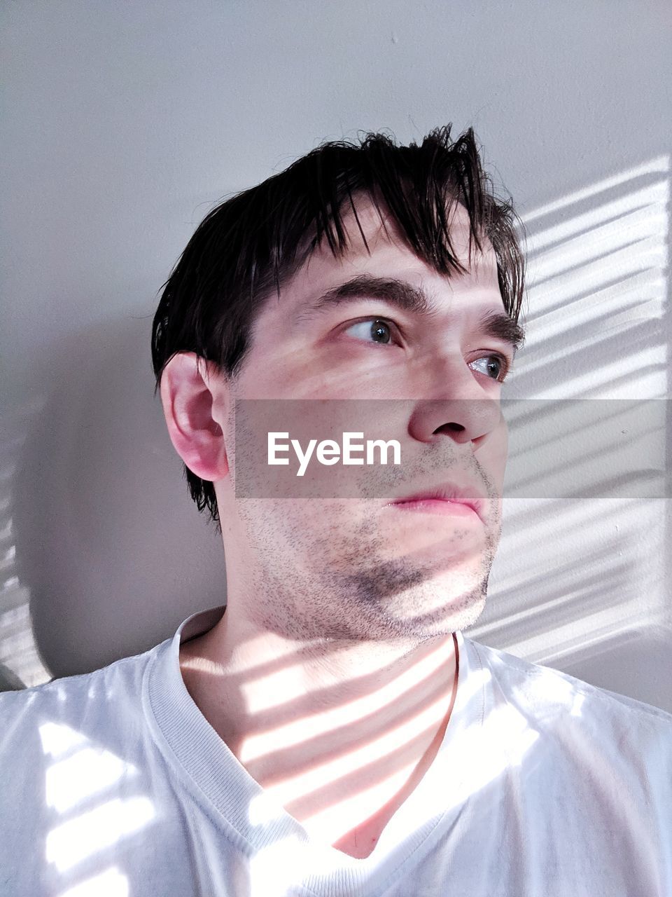 Close-up of man looking away against wall at home