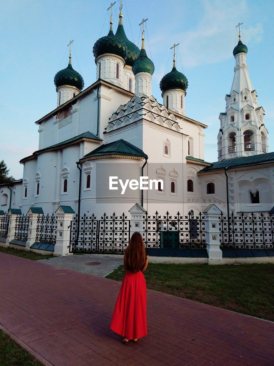 REAR VIEW OF WOMAN WALKING BY BUILDING AGAINST TEMPLE