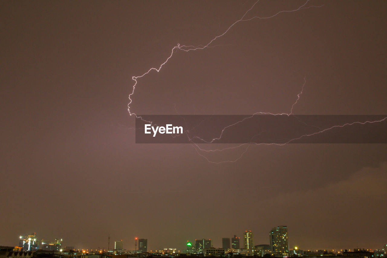Low angle view of lightning over illuminated buildings in city